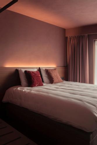 a bedroom with a large bed with red pillows at Hostellerie Kemmelberg in Kemmel