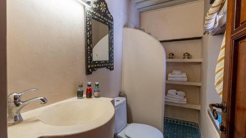 a bathroom with a sink and a toilet and a mirror at Riad Dar Pierre in Fès