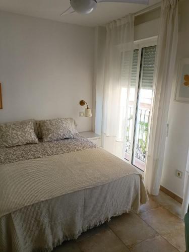 a white bedroom with a bed and a window at Plateria Catedral in Murcia