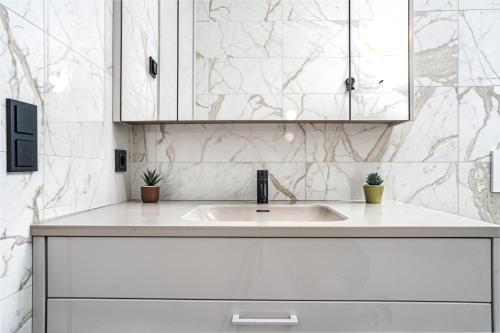 a white kitchen with a sink and marble walls at Unbeatable Central Location - Reykjavíks Most Exclusive Luxury Apartments in Reykjavík