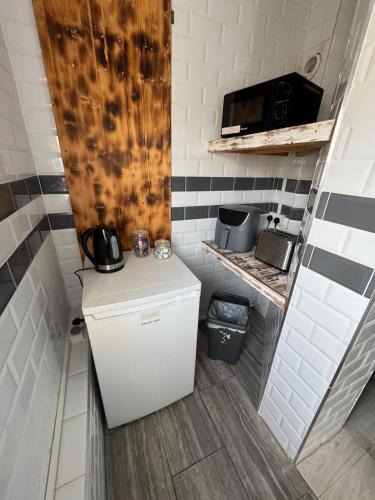 a small kitchen with a refrigerator and a microwave at OYO Shore Surf Lodge in Newquay