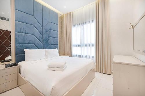 a bedroom with a white bed and a blue wall at Luxury Villa sea view and free paddle boat - Al Dana Island Fujairah in Fujairah