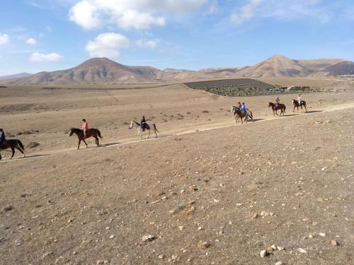 a group of people riding horses in the desert at Casita Barranco del agua in Yaiza