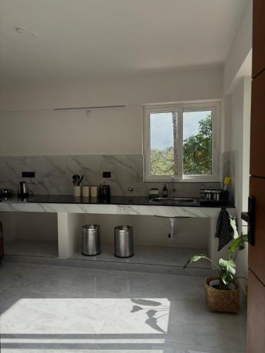a white kitchen with a sink and a window at Thira House in Varkala