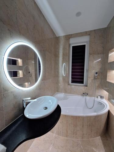 a bathroom with a tub and a sink and a mirror at Hotel Alhar in Lubliniec