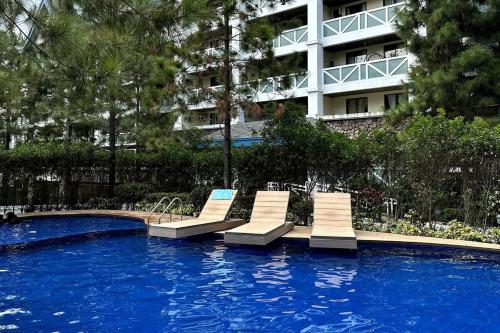 un groupe de chaises longues dans une piscine devant un bâtiment dans l'établissement Balinest Studio Tagaytay, à Tagaytay