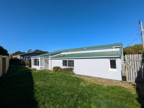 a white house with a green roof at KnT BnB in Wellington