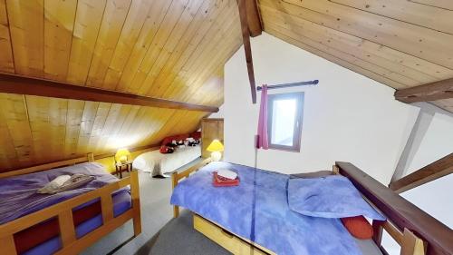 two beds in a room with wooden ceilings at Casa-Le Gerland : joli duplex dans chalet St-Véran in Saint-Véran