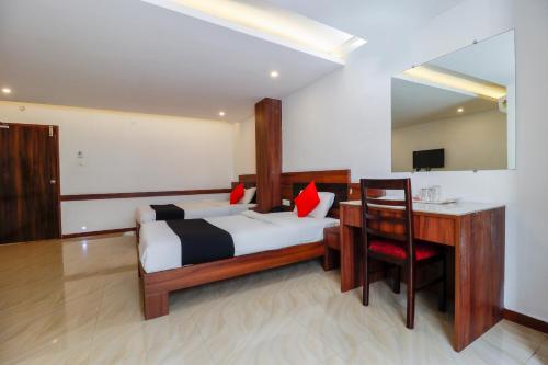 a hotel room with a bed and a desk and a desk at Capital O Sai Arya Residency in Mangalore