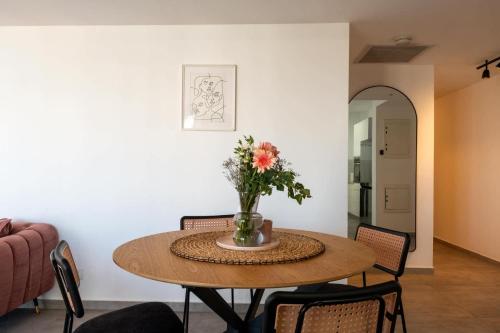 a dining room table with a vase of flowers on it at O&O Group - 3BR Skyline Retreat on the 24th Floor in Bat Yam