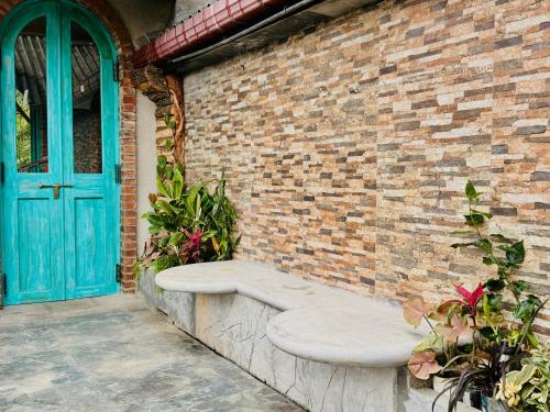 a stone bench next to a brick wall with a blue door at Awinco Haputale in Haputale