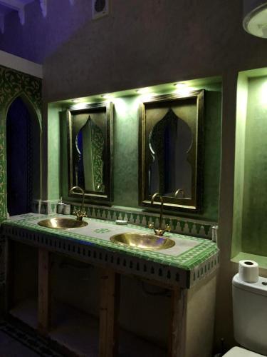 a green bathroom with two sinks and a toilet at Eden Suites 