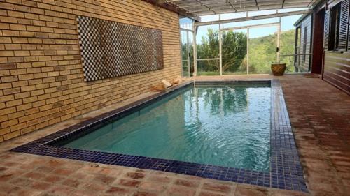 einen Pool in einem Gebäude mit Ziegelwand in der Unterkunft Wilderness Views - Clermont Cottage in Wilderness