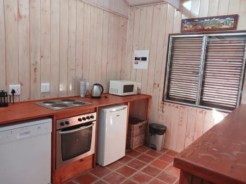 een kleine keuken met een fornuis en een magnetron bij Wilderness Views - Clermont Cottage in Wilderness