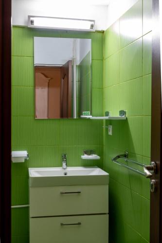 a green bathroom with a sink and a mirror at Hotel Dobrogea in Constanţa