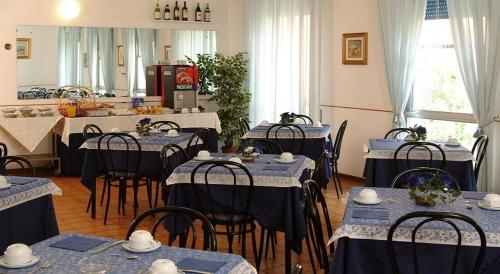 une salle à manger avec des tables, des chaises et un chiffon bleu dans l'établissement Hotel Wilma, à Rimini