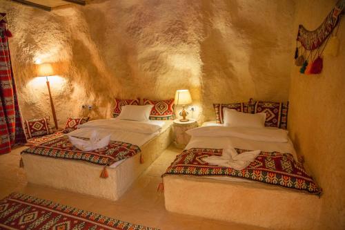 1 dormitorio con 2 camas en una habitación de piedra en Wadi Sharm Resort, en Maḩḑah