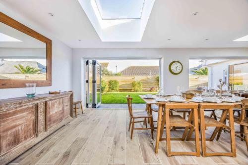 a dining room with a table and chairs and a clock at Windrocks - Bracklesham Bay in Chichester