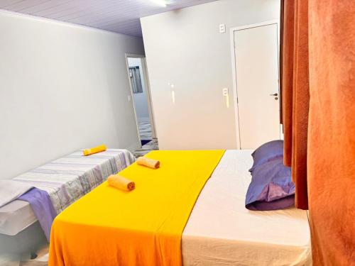 a bedroom with two beds and a yellow blanket at Uai Sô Hostel in Belo Horizonte