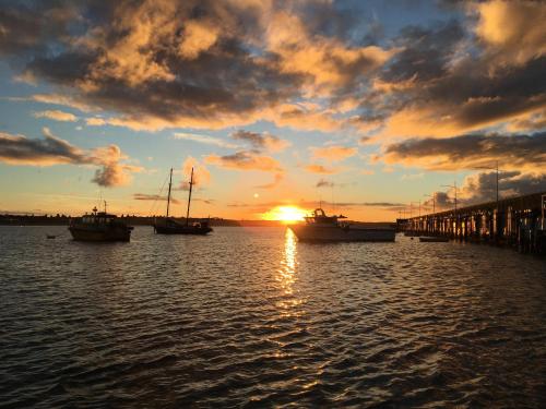 a sunset with boats in the water near a dock at Elm Tree Motel in Warrnambool