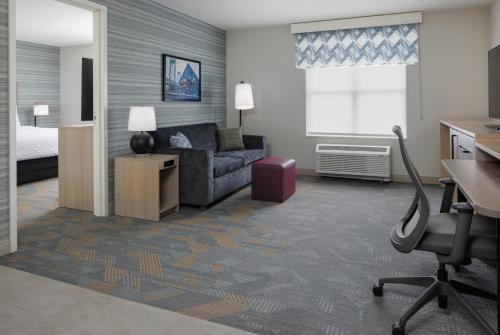 a hotel room with a bed and a couch and a desk at Home2 Suites By Hilton Kittery in Kittery