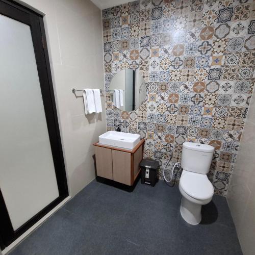 a bathroom with a toilet and a sink and a mirror at DJumah House in Ubud