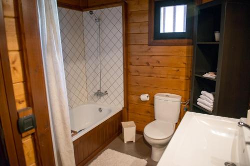 a bathroom with a toilet and a tub and a sink at Acogedora Casa de Madera con piscina in Güimar