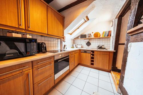 a kitchen with wooden cabinets and a microwave at Lauterbach im Herzen der Altstadt in Lauterbach