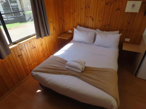 une chambre avec un grand lit avec des draps et des oreillers blancs dans l'établissement BIG4 Toowoomba Garden City Holiday Park, à Toowoomba