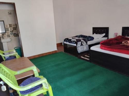 una habitación con dos camas y una mesa y sillas en Jaggi Guest House Chopta, en Chopta