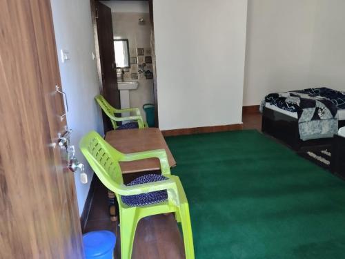 a room with two green chairs and a table at Jaggi Guest House Chopta in Chopta