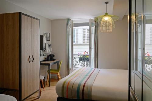 a bedroom with a bed and a desk and a window at Hotel Litteraire Marcel Ayme, BW Premier Collection in Paris