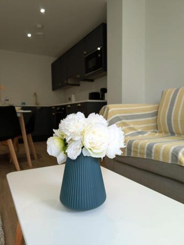 a blue vase with white flowers on a table at Leeds Arena Luxury Appt in Leeds