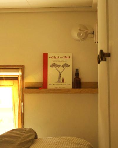 a book sitting on a shelf in a bedroom at Tiny Eco House Alba - rust, natuur en eenvoud in het Kempenbos in Diessen