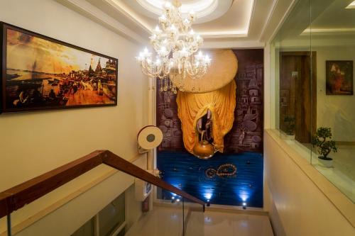 a staircase with a chandelier and a painting on the wall at Sugar Stars Inn in Varanasi