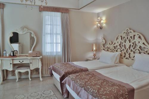 a bedroom with two beds and a table and a mirror at Elegance East Hotel in Antalya