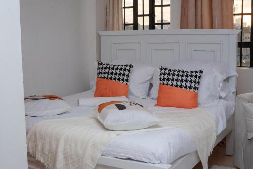 two beds in a room with orange and white pillows at Couple-Friendly Studio Apartment In Pangani in Nairobi