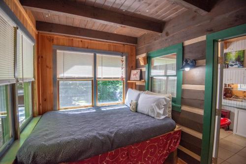 a bedroom with a bed in a room with windows at Secluded 2 Bd Cabin- Firepit, Hot Tub, Dogs OK, Sleeps 6 in Baldwin