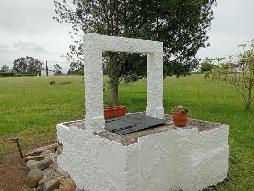 a white structure with two pots on it in a field at Casa De la Agüera in Busto