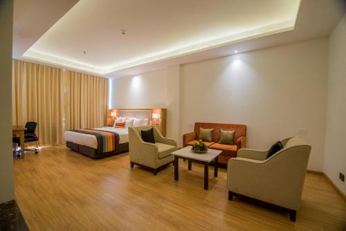 a hotel room with a bed and a couch and chairs at The Imperial Poonam Hotel in Phagwāra