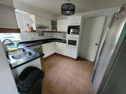 a kitchen with white cabinets and a sink and a refrigerator at Linda casa condominio in Santiago