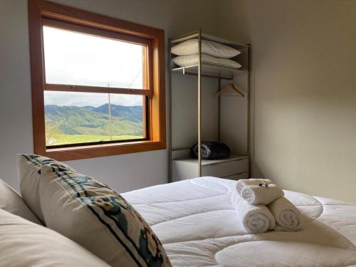 a bedroom with a white bed with a window at Casa de Campo - Quintal Infinito in São Luiz do Paraitinga