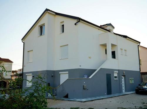 a white building with a staircase on the side of it at Apartmani Dusper in Vodice