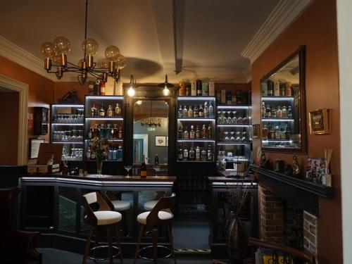 a bar with two stools and a mirror in a room at East Walls Hotel in Chichester