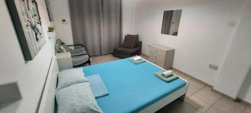 a small room with a blue bed and a chair at Magic Sea Apartments in Larnaka