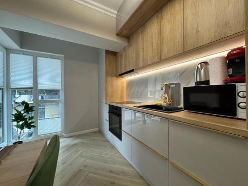 a kitchen with white cabinets and a microwave at Iassy Airport Luxury Apartments with Parking in Iaşi