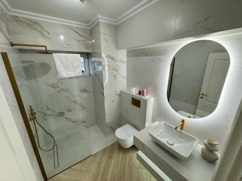 a white bathroom with a sink and a mirror at Iassy Airport Luxury Apartments with Parking in Iaşi