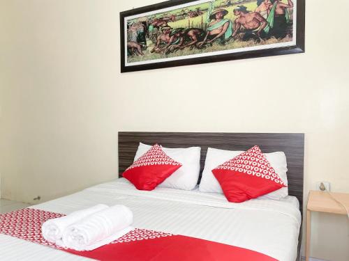a bedroom with a bed with red and white pillows at Hotel O Kate'el Inn in Banyuwangi