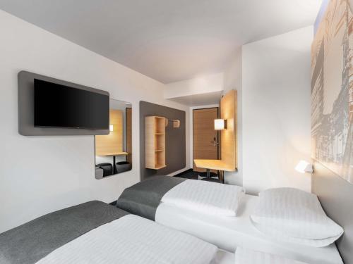 a bedroom with two beds and a flat screen tv at B&B HOTEL St-Pölten in Sankt Pölten