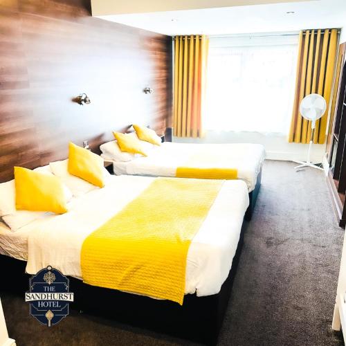 two beds in a hotel room with yellow and white sheets at The Sandhurst Hotel in Blackpool